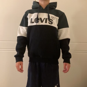 Levi's hoodie i svart och vitt - Snygg hoodie från Levi's med svart och vit färgblockdesign och stor logga framtill. Tröjan har huva, dragsko och känguruficka.  Mjuk och skön bomullsblandning, långärmad och normal passform.