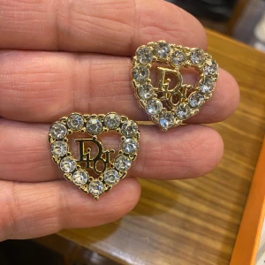  hjärtformade örhängen med strass - Superfina hjärtformade örhängen  i guldton med stora glittrande strass-stenar runt kanten. . Perfekta för dig som vill sticka ut och addera lite extra bling till din look.