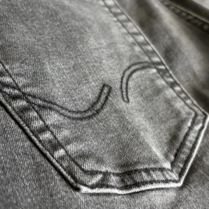 Grå jeans från Jack & Jones, stl 152 - Snygga grå jeans från Jack & Jones i storlek 152. Klassisk femficksmodell med raka ben och diskret broderi på bakfickorna. Jeansen är tillverkade i bomull med en liten del stretch för extra komfort. Perfekta för dig som gillar en stilren look. Passar även folk som är 158-164 eftersom dessa jeansen är gjort lite stora 