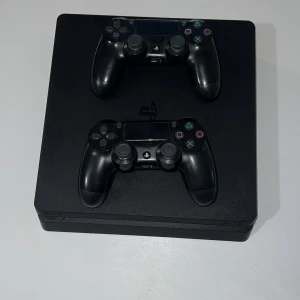 PlayStation 4 Slim - Sony PlayStation 4 Slim i gott skick med två original DualShock 4-kontroller och HDMI-kabel. Konsolen och kontrollerna visar mindre bruksspår men är fullt fungerande. Perfekt för spelkvällar och underhållning hemma. Skick eller så hämtar man varan 