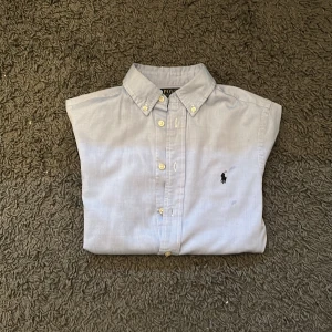 Ralph Lauren skjorta - Riktigt snygg och stilren Polo Ralph Lauren  skjorta i färgen ljusblå. Köpt från Kidsbranstore och skicket är 9/10 utan några defekter. Storleken är 16 och passar dig som är mellan 160-170 cm. Pris kan diskuteras. Det är bara och skriva om ni har några ytterligare frågor!🙌