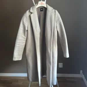 Beige kappa från Zara  - Stilren beige kappa från Zara i klassisk rak modell med krage och lång ärm. Kappan och har en mjuk, lite borstad yta. Perfekt för dig som gillar minimalistisk och clean stil.🌸