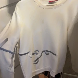 Vit sweatshirt från Hugo Boss - Vit sweatshirt från Hugo Boss med grått tryck i form av ett stiliserat mönster över bröstet och ena ärmen. Tröjan har rund halsringning och långa ärmar. Perfekt för en clean och modern look. Storlek M men passar även S. Nypris: 1700 väldigt sälsynt