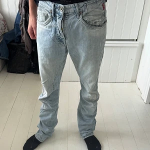 Ljusblå jeans från Jack & Jones - Säljer ett par ljusblå jeans från Jack & Jones, modell Stan Nico. Jeansen har klassisk femficksdesign, raka ben och snygga slitningar för en avslappnad look. Tillverkade i bomull med dragkedjegylf och diskreta detaljer på bakfickorna. Det är bara att höra av dig vid frågor!