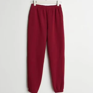 Gina Tricot Basic Sweatpants - Vinröda mjukisbyxor med elastisk midja och muddar vid bensluten. Byxorna har en loose passform och är tillverkade i mjukt bomullsmaterial, perfekta för chill dagar. Snygg och enkel design utan synliga loggor eller detaljer.