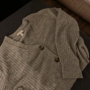 Beige ribbad kofta med knappar - Mysig beige kofta från H&M med ribbad struktur och stora knappar framtill. Koftan har lång ärm och v-ringning, perfekt att slänga på sig när det är kyligt. Speciellt nu till hösten 🍂🤎Enkel och stilren design som funkar till det mesta. Använd 2-3 gånger ca. 