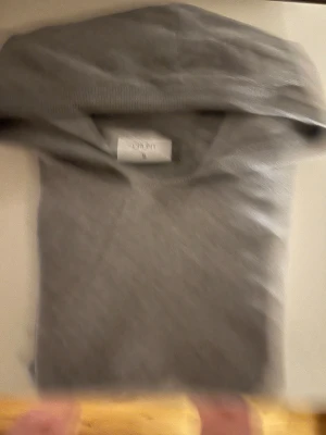 Stickad grå hoodie. - En enkel och stilren grå hoodie från Grunt i storlek 170/176 Passar även mindre storlekar. Tröjan har en klassisk huva och långa ärmar, samt ribbade muddar vid ärmslut och nederkant. Perfekt för chill dagar och passar till det mesta. Materialet känns mjukt och bekvämt mot huden.      (OBS, kan tänka att gå ner i pris.)