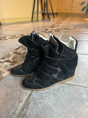Svarta wedge sneakers med kardborre - Säljer ett par Isabel marant liknande skor! De är svarta gjorda i mocka och skinn med en vit insida. Storlek 39. Säljer pga att dem knappt kommit till användning, köpte de förra sommaren men har nog använt dem 1-2 gånger så inga defekter alls! Hör av dig om du har några frågor💗💕
