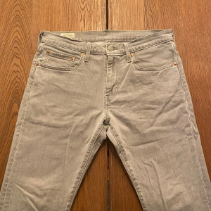 Grå Levi's 511 jeans W31 L32 - Snygga grå Levi's 511 jeans med klassisk femficksdesign och ikonisk röd Levi's-tag på bakfickan. Jeansen har en slim passform och är tillverkade i mjukt bomullsmaterial. Perfekt för dig som gillar stilrena och moderna jeans.