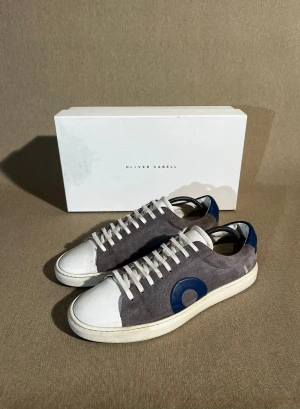 Oliver Cabell - En av de populäraste skorna på marknaden av en anledning. Unika skor med en perfekt design.   Storlek: 41 | Färg: Grå & Vit | Skick: Mycket bra (små tecken på toe capen & insidan) | Material: Mocka | Tillbehör: Box, Dustbag & Kvitto | Pris: 1999kr | Dm för frågor.