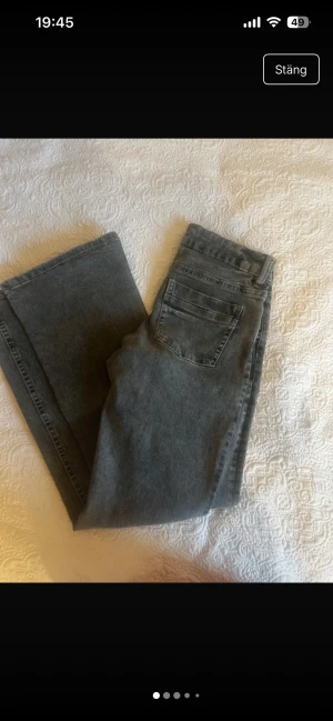 Grå bootcut jeans från Gina Tricot - Snygga grå jeans från Gina Tricot i storlek 164. Modellen har klassisk femficksdesign, normal passform och bootcut-ben som ger en cool siluett. Jeansen är tillverkade i mjukt denimtyg och har knapp och dragkedja framtill.