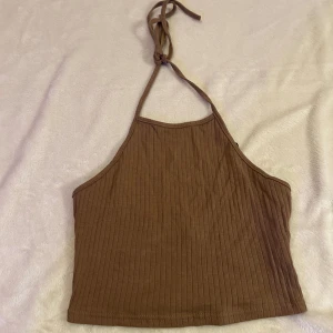 Brun topp - Säljer en helt ny, oanvänd brun topp som knyts runt halsen, i storlek XS/34.🩷