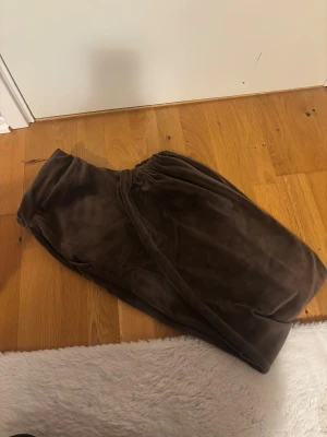 Bruna mjukisbyxor i sammet - Säljer ett par bruna mjukisbyxor i mjuk och skön sammet. Byxorna har en relaxed passform med resår i midjan och är perfekta för chill dagar hemma. Färgen är mörkbrun och materialet känns riktigt lyxigt mot huden.