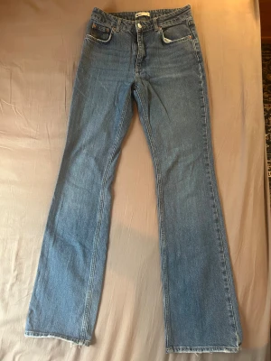 Blå jeans från gina tricot, storlek 38 - Snygga blå jeans från gina tricot perfect jeans kollektion i storlek 38. Klassisk femficksmodell med raka ben. Jeansen har dragkedja och knapp framtill, och är gjorda i robust denim. De är lite slitna längst ner vid benen då de varit för långa för mig. 