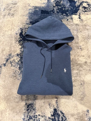 Blå Ralph Lauren Hoodie - Riktigt fet Ralph Lauren hoodie i storlek L. Han på bild är 185cm, 75kg. Bra skick förutom en liten fläck som säkert går bort i tvätt. Pris kan diskuteras vid snabb affär!