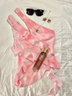 Rosa omlott topp från LeGer | - Säljer en drömmig rosa omlott topp från LeGer med volangdetaljer och oneshoulder-design. Säljer då jag har växt ut den. Jag är 174cm och toppen är i storlek 34. Köpte ny för 515kr. Skulle passa någon som är stl XS/34.