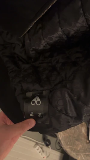 Äkta Svart teddyjacka Moose Knuckles L kommer med hängaren - Svart teddyjacka från Moose Knuckles i storlek L. Jackan har vit fluffig fuskpäls på insidan av huvan, dragkedja framtill och ikonisk logga på ärmen. Snygg och varm med två fickor och quiltad insida med mönster. Perfekt för kalla dagar. Pris kan diskuteras 