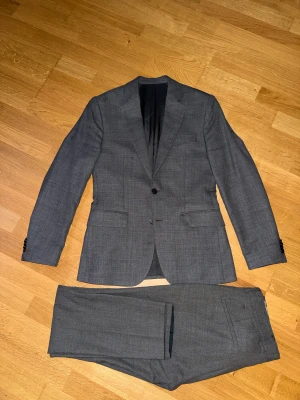 J.Lindeberg grå kostym - Grå kostym från J.Lindeberg,  Modell: Active hopsack Kavaj storlek: 44 Byx storlek: 46 Nypris: 6500kr Nyskick, inga slitage eller defekter.