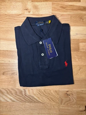 Polo Ralph Lauren Slim Fit T-shirt – Mörkblå  - Snygg och klassisk Polo Ralph Lauren T-shirt i mörkblå. Modellen är Slim Fit och sitter perfekt på kroppen. Originalkvalitet, aldrig använd – helt ny i toppskick. Pris kan diskuteras så klart