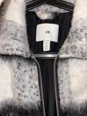 Rutig teddyjacka från H&M i S - Säljer en fluffig teddyjacka från H&M i storlek S. Jackan har ett rutigt mönster i svart, grått och vitt, med dragkedja framtill och två sidofickor. Materialet är mjukt och teddy-liknande, perfekt för dig som gillar chill och cozy vibes. 