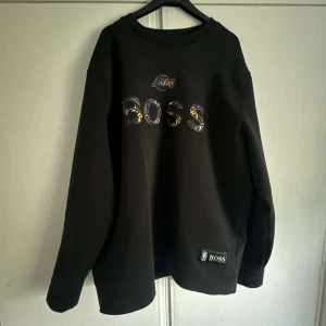 Hugo boss X NBA - Skick: Bra skick  Passform: Normal passform  Färg: svart med gul, lila och vita detaljer Köpt: 2 år sen : ( Johnells Norrköping) Nypris: 1700kr Använder inte längre för att den tyvärr är för stor för mig.