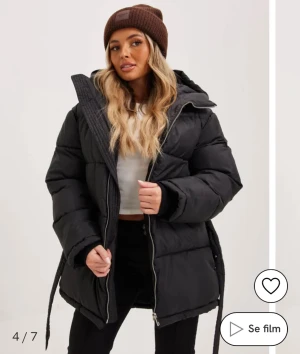 Svart pufferjacka med huva och bälte - Säljer en svart pufferjacka med huva och bälte i midjan. Jackan har quiltad design, dragkedja framtill och långa ärmar. Perfekt för kalla dagar och har en loose passform. Köpt för 800.