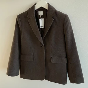 Mörkbrun jacka  - Snygg mörkbrun kavaj / jacka från H&M med klassisk krage och enkel knappstängning. Snygg och stilren.