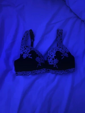 Svart spetsig korsett med blommönster - Säljer en svart korsettliknande topp med breda axelband och vacker spets i blommönster. Spetsdetaljerna går längs både kanter och axelband, vilket ger en romantisk vibe. Perfekt för dig som gillar detaljer och vill ha något extra.