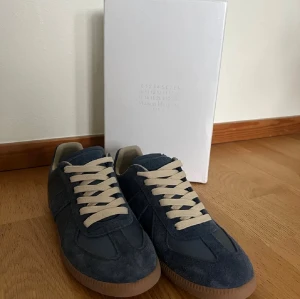 Maison Margiela blå sneakers - Maison Margiela sneakers i mörkblå mocka. stilren design som passar till jeans eller dressade outfits. Kommer med originalkartong och dustbags.