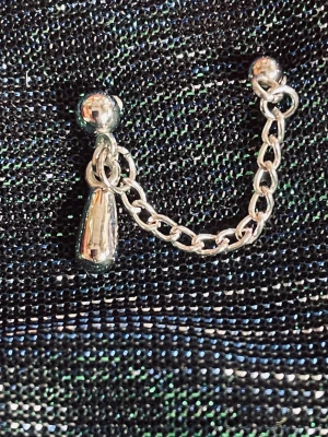 By prisförslag- 1 st Silvrigt dubbel örhänge med kedja - Coolt örhänge i silverfärgad metall med en kort kedja som länkar ihop två små kulor. Ena sidan har en droppformad detalj som ger extra edge. Perfekt för dig som gillar minimalistisk men ändå unik stil.