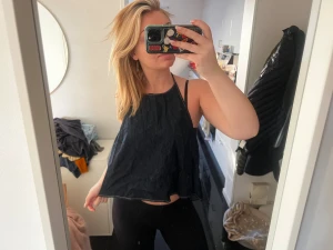 Blå ärmlös jeanstopp - Säljer en marinblå, luftig och ärmlös linnetopp med smala axelband och avslappnad passform. Öppen i ryggen