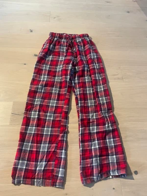 Mjukisbyxor - Säljer ett par chill röda mjukisbyxor med klassiskt rutigt mönster och snörning i midjan. Byxorna har breda ben och elastisk midja för extra komfort. Perfekta för att hänga hemma eller mysa med vänner. De är från Gina Tricot i storleken 146/152 men jag har klippt bort lappen för den skavde.