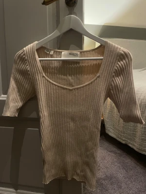 Beige ribbad topp från Selected Femme - Säljer min beigea ribbade topp från Selected Femme med v-ringad hals och halvlånga ärmar❣️Toppen är något nopprig men är fortfarande superfin då det inte är något man lägger märke till!