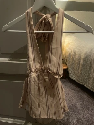 Beige randig topp - Superfin beige topp med bruna och grå ränder. Toppen knyts med breda band i nacken och är öppen i ryggen!😻har tyvärr inte kvar lappen på storlek men passar mig som vanligtvis bär strl S perfekt!