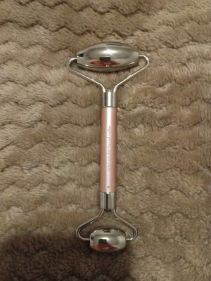 Real Techniques cryo sculpt facial roller - Face roller från Real Techniques i metallic rosa och silver. Rollern har två släta metallhuvuden och ett greppvänligt handtag i aluminium. Perfekt för att ge ansiktet en fräsch känsla och boosta din hudvårdsrutin.