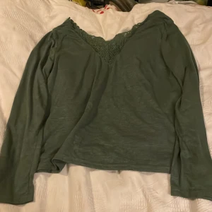 Grön långärmad blus med spets - Säljer en så snygg grön långärmad blus/ltröja   med v-ringad hals och snygga spetsdetaljer framtill. Blusen har en mjuk känsla och är perfekt för dig som gillar stilrena plagg med lite extra detaljer. Passar dig som vill ha en chill men ändå snygg look.Även v-ringad bak.