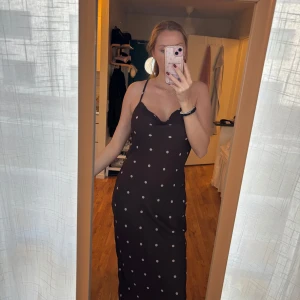 Brun prickig långklänning  -  Brun långklänning med vita prickar och smala axelband som korsas i ryggen från ASOS.                              Helt ny med prislapp kvar, nypris 599kr. 