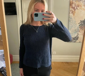 Mörkblå glittrig stickad tröja - Snygg mörkblå stickad tröja med glitter och ribbad struktur. Tröjan har en liten slits på sidan.