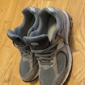 Grå New Balance 2002R sneakers - Säljer ett par grå New Balance 2002R sneakers i storlek 44.5. Skorna har meshpaneler och detaljer i mocka, med klassisk N-logga på sidan. De har snörning och en bekväm, stötdämpande sula som passar perfekt för en aktiv livsstil. Inte använt skorna mycket så de är i bra skick och nya