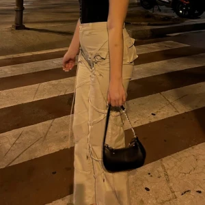 Beige cargopants från Luxe To Kill - Säljer ett par beige cargopants från Luxe To Kill i storlek EU 38. Byxorna har hög midja, breda ben och coola snörningsdetaljer längs sidorna samt flera fickor. 