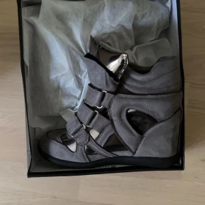 Grå wedge sneakers Isabel marant liknande  - Säljer ett par Isabel marant liknande grå wedge sneakers med coola metallicdetaljer och kardborreband. Helt oanvända endast testade och kommer i sin skokartong! ❤️storlek 37