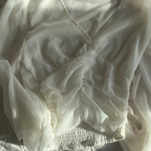 Vit omlottblus från Bik Bok - Säljer en superfin vit omlottblus från Bik Bok i storlek S. Blusen har långa, luftiga ärmar och smockad midja. Tunt, lätt material med snygg struktur och v-ringad hals. Perfekt för dig som gillar romantiska och trendiga plagg.