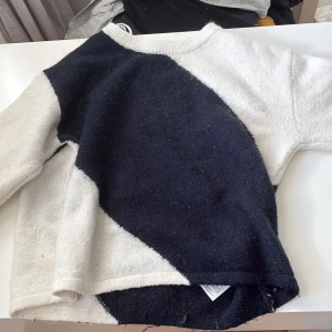 Svartvit stickad tröja Gina Tricot - Snygg stickad tröja från Gina Tricot i svart och vitt med coolt blockmönster. Tröjan har rund halsringning och långa ärmar, perfekt för att hålla sig varm och stilren under kyliga dagar.