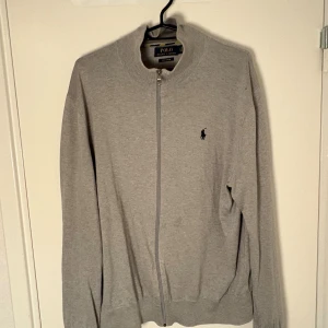 Grå ziptröja från Polo Ralph Lauren - Snygg grå ziptröja från Polo Ralph Lauren i mjuk pima bomull.Plagget har en liten fläck som förmodligen går bort. Priset kan även diskuteras då jag försöker bli av med så mycket kläder som möjligt