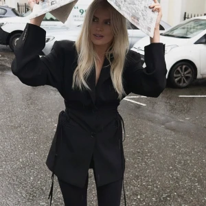 Svart kavaj med snörningsdetaljer - Säljer en svart kavaj med knytten på sidorna där man kan dra åt eller inte. Andvänd bara 1 gång så super fint skicka slutsåld! 