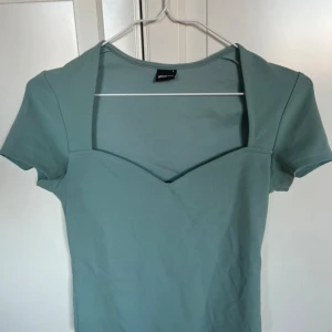 Grön topp med v-ringning Gina Tricot - Snygg ljusgrön topp från Gina Tricot med korta ärmar och hjärt-ringad hals. Toppen har en figurnära passform. Endast använd 1 gång 💚