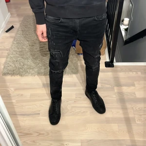 Svarta jeans med slitningar och paintsplatter - Hej! Säljer dessa riktigt feta svarta jeansen med slitningar och paintsplatter! Slim passform i storlek 31/30. None branded. Passar perfekt på mig som är 180cm och väger ca 67kg