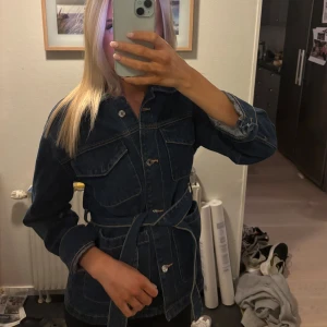 Mörkblå jeansjacka med bälte från MNG - Säljer en jättesnygg mörkblå jeansjacka/tröja från MNG med bälte i midjan. Jackan har knappar framtill och långa ärmar. Perfekt för dig som gillar en klassisk men trendig look, samt perfekt nu till hösten ❣️ Storlek XXS, men passar allt ifrån XXS-M. Som referens brukar jag ha S 💓