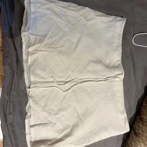 Vit omlottkjol från H&M Divided - Säljer en vit kort linnekjol från H&M Divided i storlek S. Kjolen har en enkel och clean look med knytband i midjan. Materialet känns lätt och har en diskret struktur, perfekt för dig som gillar minimalistisk stil. Säljer då den är för stor.
