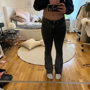 Svarta bootcut jeans med låg midja  - Säljer ett par svarta bootcut jeans med låg midja. Jeansen har klassisk femficksdesign och är i stretchigt denimtyg som sitter tajt upptill och släpper ut vid bensluten. Perfekta för dig som gillar en snygg siluett och vill ha en modern look.